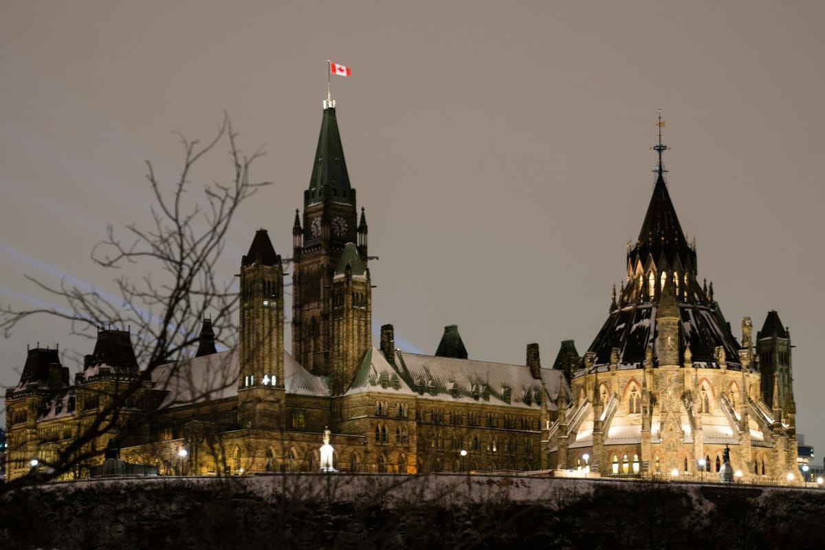 Canada’s Parliament Buildings illuminated at night in Ottawa, with the Canadian flag flying above the Peace Tower.