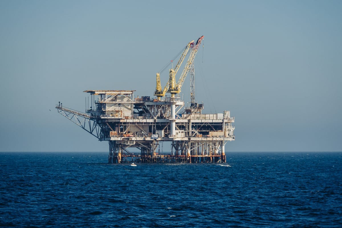 Offshore oil and gas platform with a large crane standing in open ocean waters.