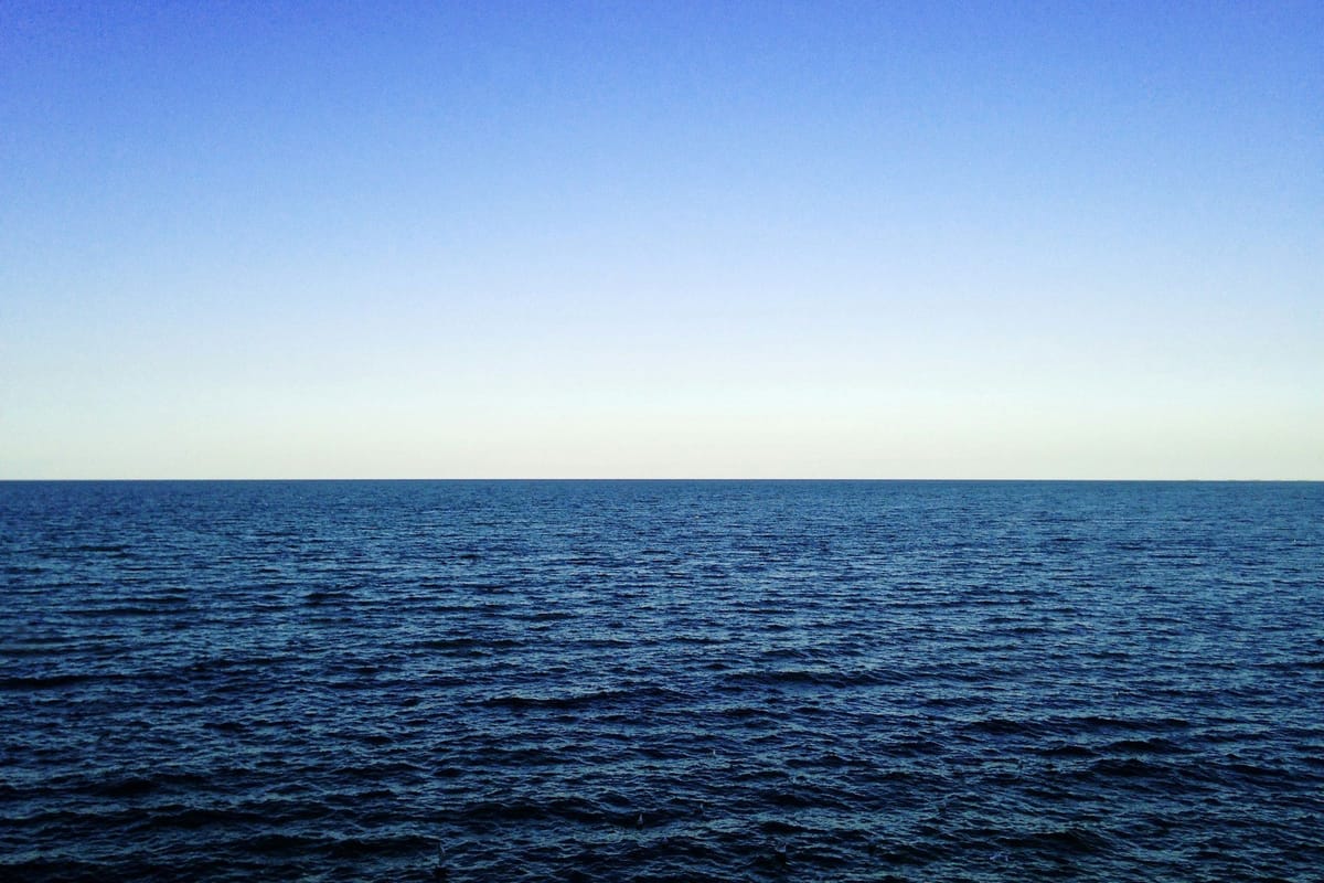 Open ocean stretching to the horizon beneath a clear blue sky.
