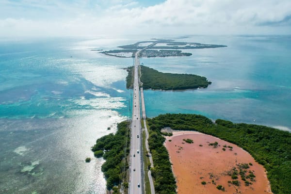 Aerial view of a coastal highway crossing low-lying islands and shallow turquoise waters.