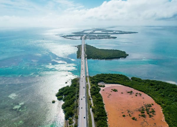 Aerial view of a coastal highway crossing low-lying islands and shallow turquoise waters.