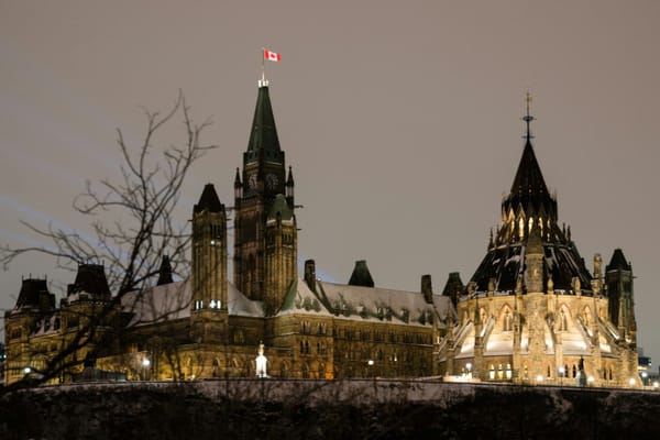 Canada’s Parliament Buildings illuminated at night in Ottawa, with the Canadian flag flying above the Peace Tower.