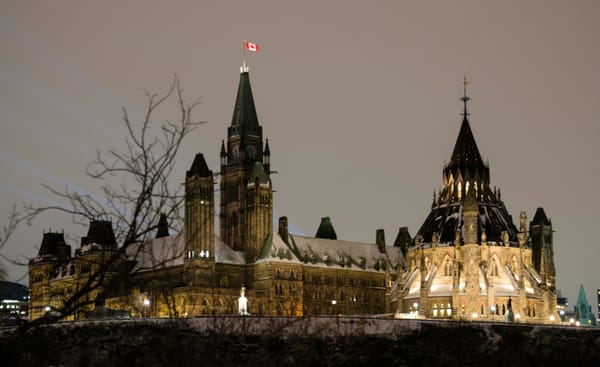 Canada’s Parliament Buildings illuminated at night in Ottawa, with the Canadian flag flying above the Peace Tower.