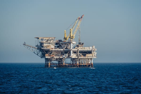 Offshore oil and gas platform with a large crane standing in open ocean waters.