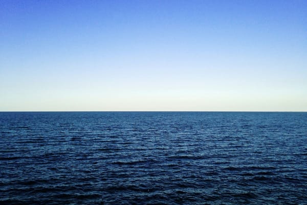 Open ocean stretching to the horizon beneath a clear blue sky.
