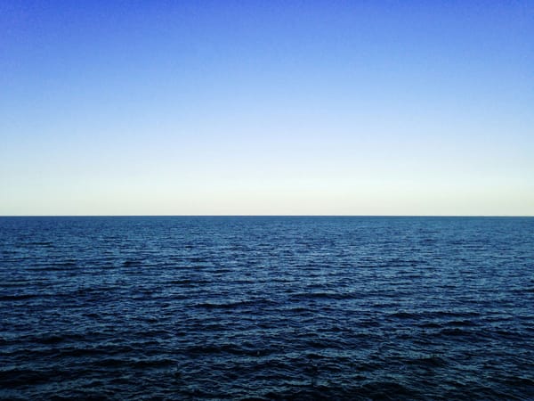 Open ocean stretching to the horizon beneath a clear blue sky.