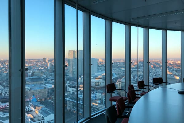 Empty modern boardroom overlooking a city skyline through floor-to-ceiling windows.