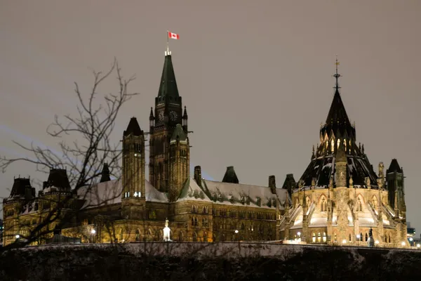 Canada’s Parliament Buildings illuminated at night in Ottawa, with the Canadian flag flying above the Peace Tower.