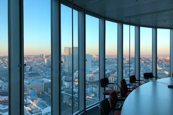 Empty modern boardroom overlooking a city skyline through floor-to-ceiling windows.